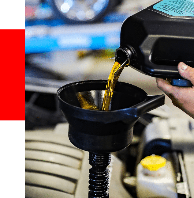 oil change services at Barrett Automotive close up of technician pouring fresh oil into funnel located at the top of a vehicle engine for an oil change in the shop